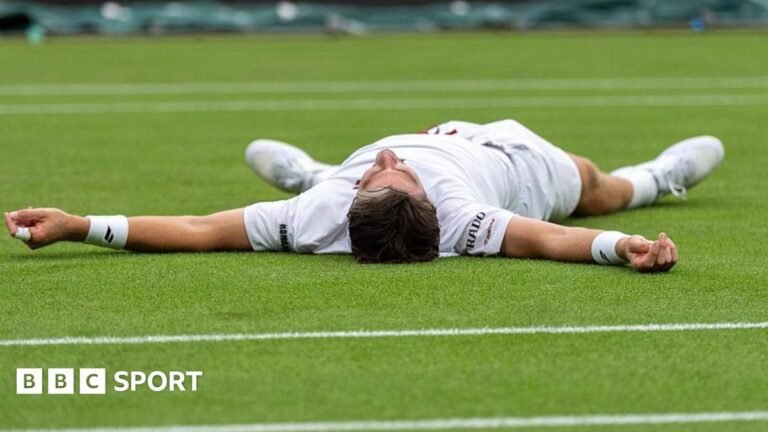 Cameron Norrie celebrates by falling on to the court